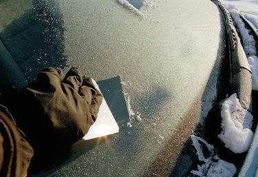 Person scraping frost off a car windshield