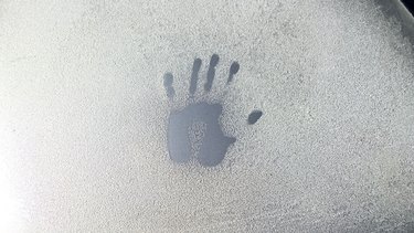 Closeup of handprint on frozen car windshield
