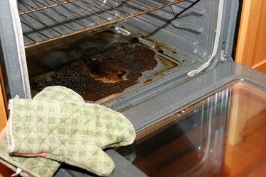 Oven door open, revealing blackened, baked-on spills