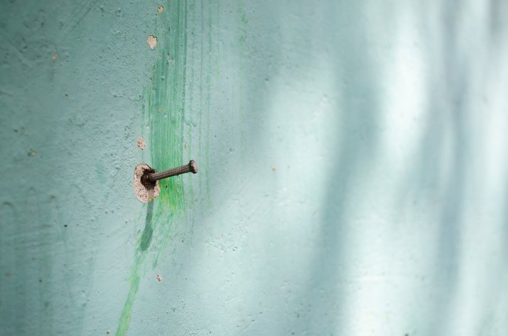 Nail on a green wall.