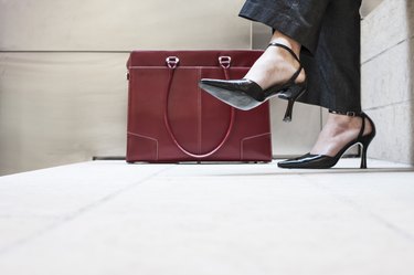 Businesswomans feet in high heeled shoes and her purse.