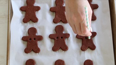 Cutting holes in gingerbread men for ribbon