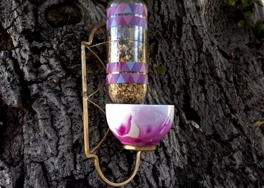 DIY bird feeder made from wrought iron candle sconce and teacup.