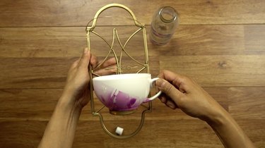 Attaching teacup to candle sconce for DIY bird feeder made from wrought iron candle sconce and teacup.