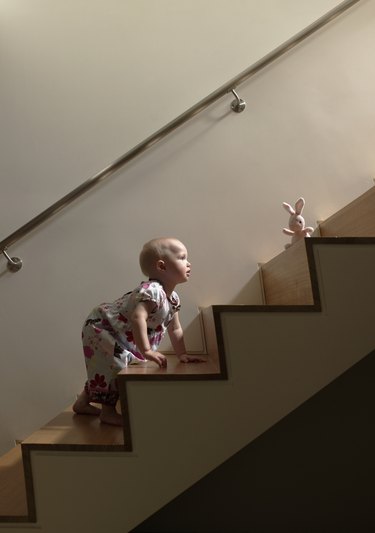 Baby girl climbing stairs to get toy
