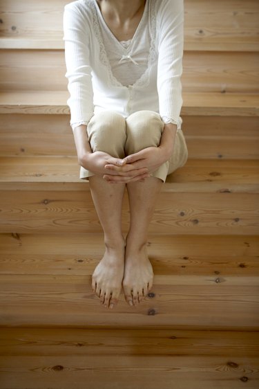 Woman with bare feet, sitting on wooden stairs in home