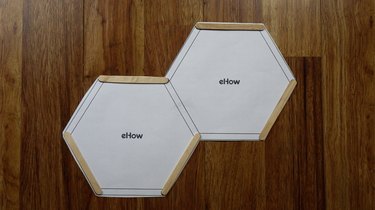 Using a printed template to create popsicle stick DIY hexagon shelves.