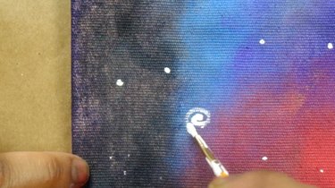 Painting a spiral galaxy on a cushion cover.