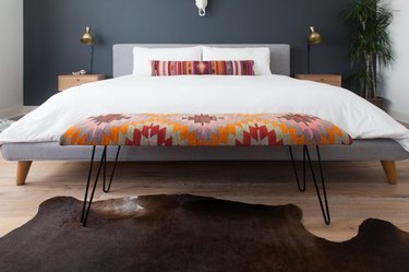 Kilim patterned rug bench at the end of a large bed
