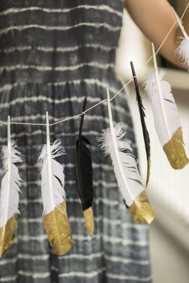 Black and white feathers with the ends painted gold tied into a garland