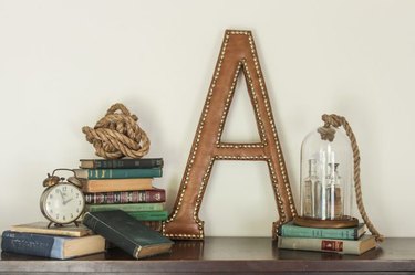 A letter "A" leather monogram next to stacks of books