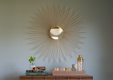 A gold sunburst mirror over on a gray wall