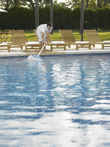 Man cleaning hotel outdoor pool with net