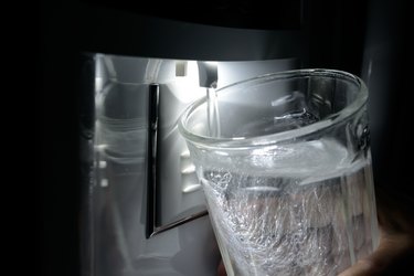 Glass being filled at refrigerator water dispenser