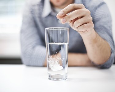 Man dropping antacid into a glass of water