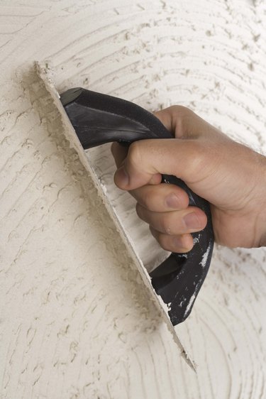 Person putting grout on wall with trowel