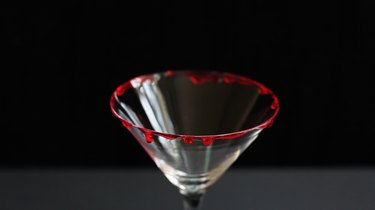 Red corn syrup dripping down rim of glass