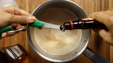 Adding flavoring extract into saucepan for sugar-free Irish cream liqueur.