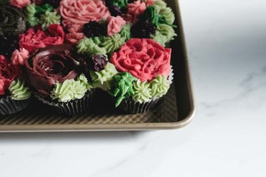 Cupcakes carefully piped with icing to resemble decorative clusters of small succulents and cacti.