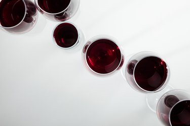 top view of red wine in glasses arranged isolated on white