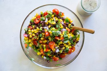 Corn salad in a bowl with dressing on side