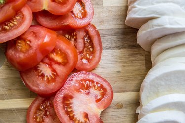 slices of tomato and fresh mozzarella on a cutting board