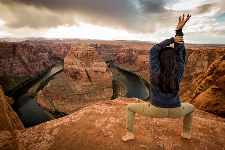 back of girl doing yoga pose on edge of cliff at horseshoe bend in Arizona
