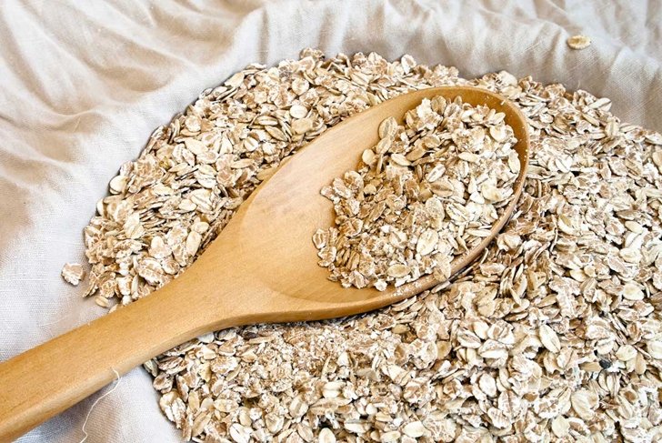 Dry rolled oats seed in wooden spoon